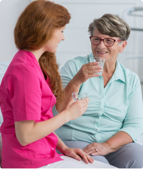 caregiver giving medication to elderly patient